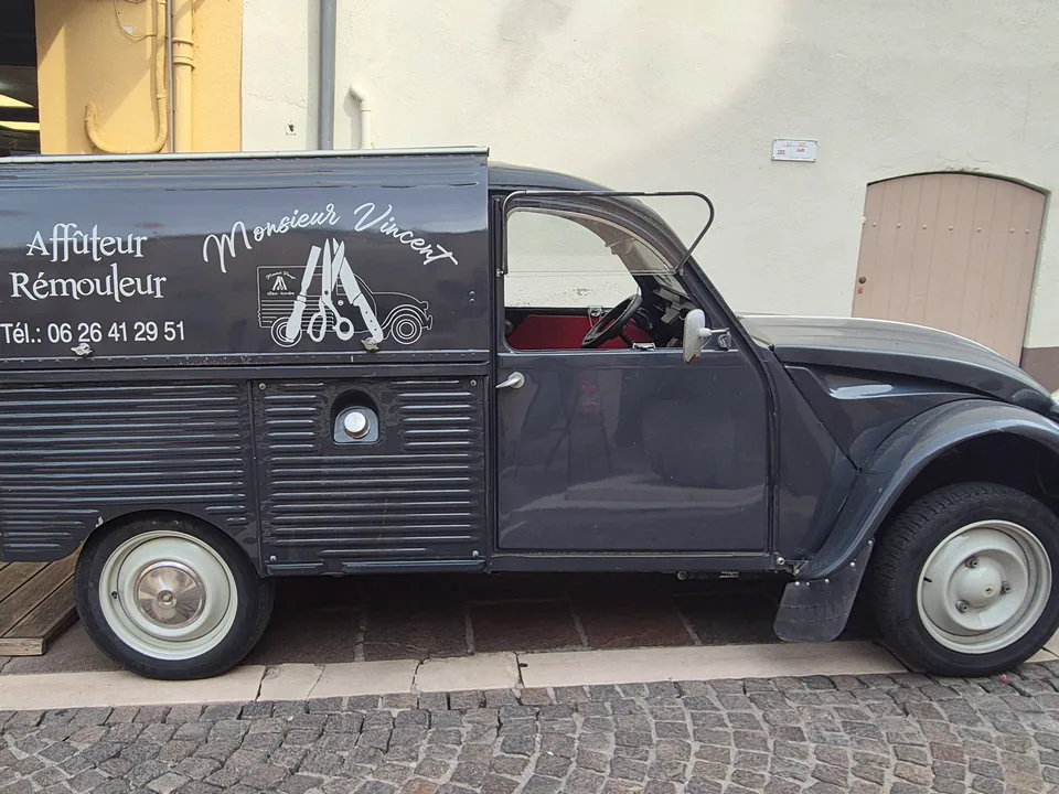 La camionnette-atelier de Monsieur Vincent, affûteur-rémouleur, garée devant la boutique