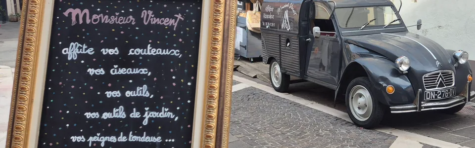 L'ardoise de Monsieur Vincent et sa camionnette-atelier devant la boutique
