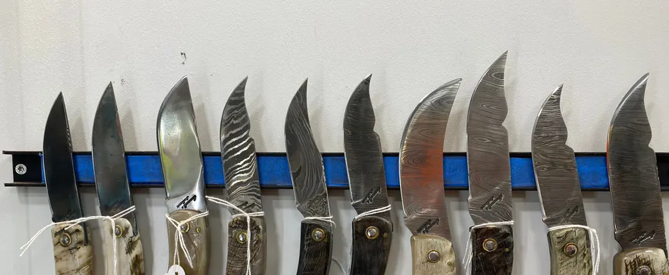 Couteaux à manche en corne et lame damas présentés en boutique