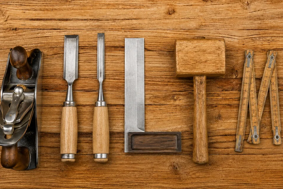 Rabot, ciseaux à bois, équerre et maillet de menuisier alignés sur un établi